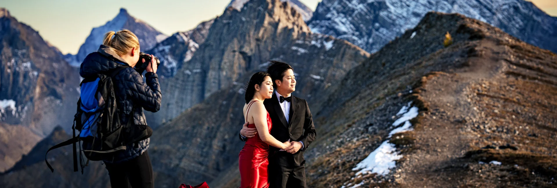 Photographers takes photo of couple at the top of the mountain