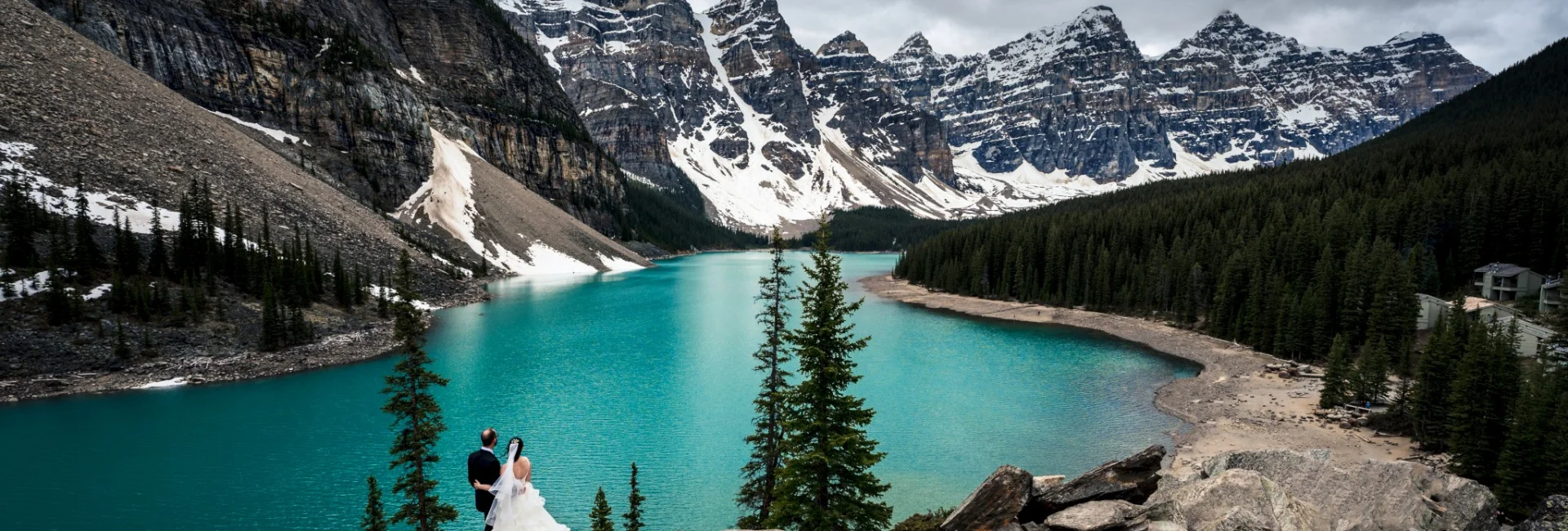 Bride and groom stand on the rock at Moraine Lake