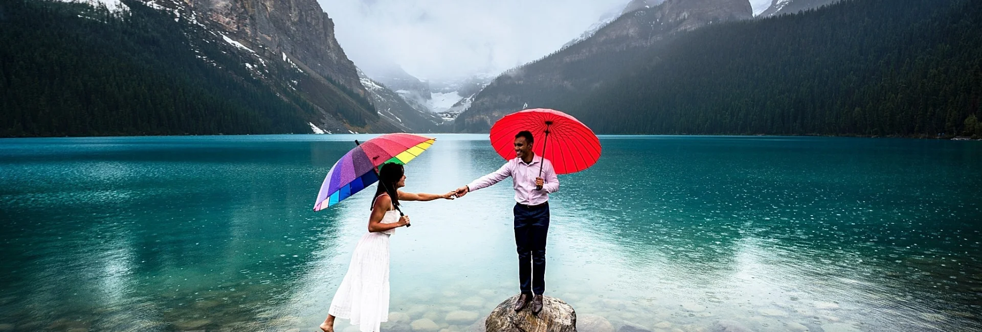 Bride and groom stand on the rocks at Lake Louise