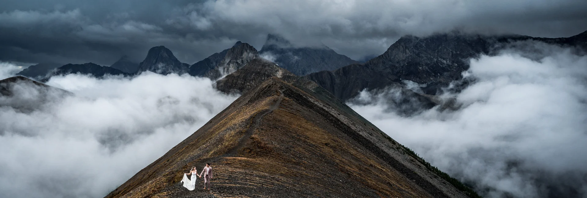 Bride and groom are walking on the ridge of the mountain