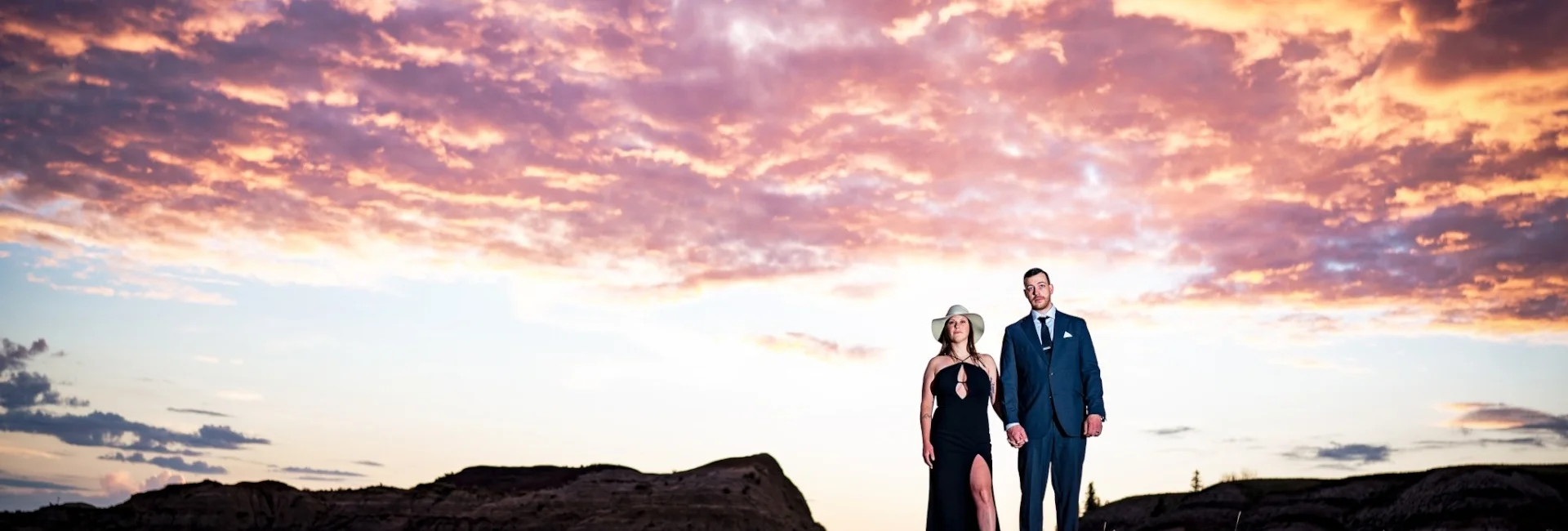 Engaged couple stand on the horseshoe Canyon . Above their heads stunning, colourful clouds.