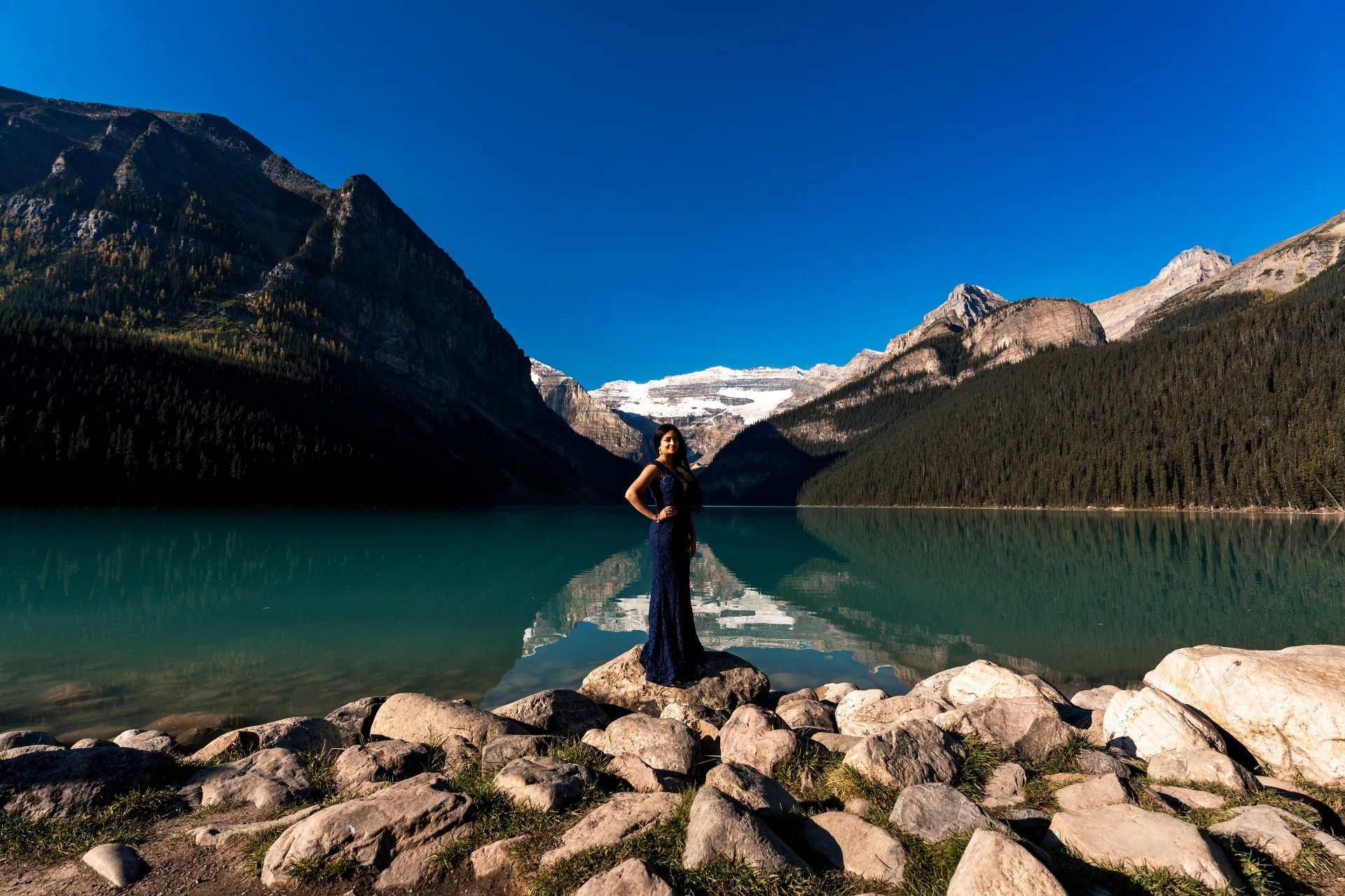 Beautiful in a purple long reass standing at the Lake Louise shore
