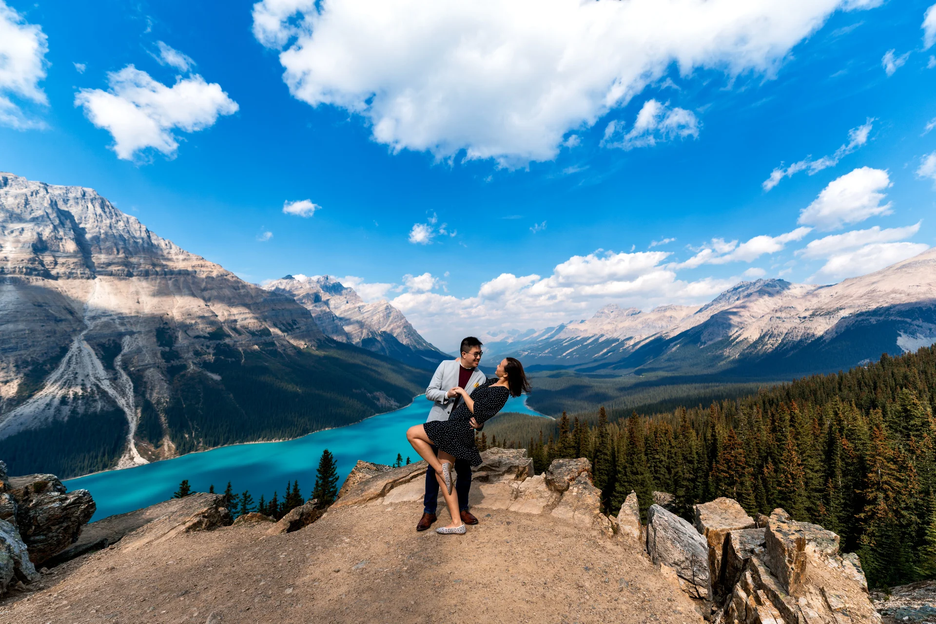 Engaged couple in love dance at Payto Lake against Rocky Mountains.