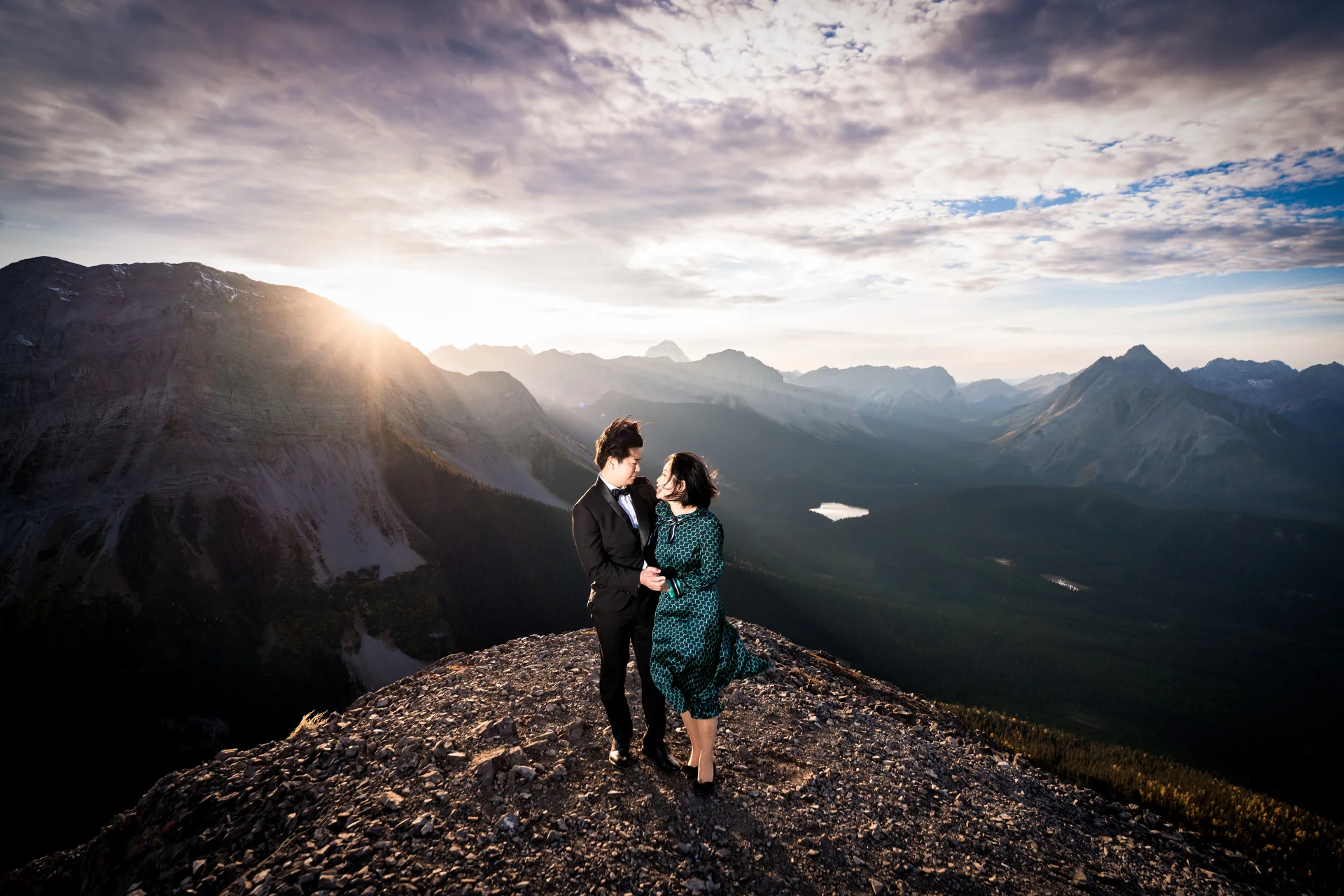 Engaged couple look at each other at the top of the mountain
