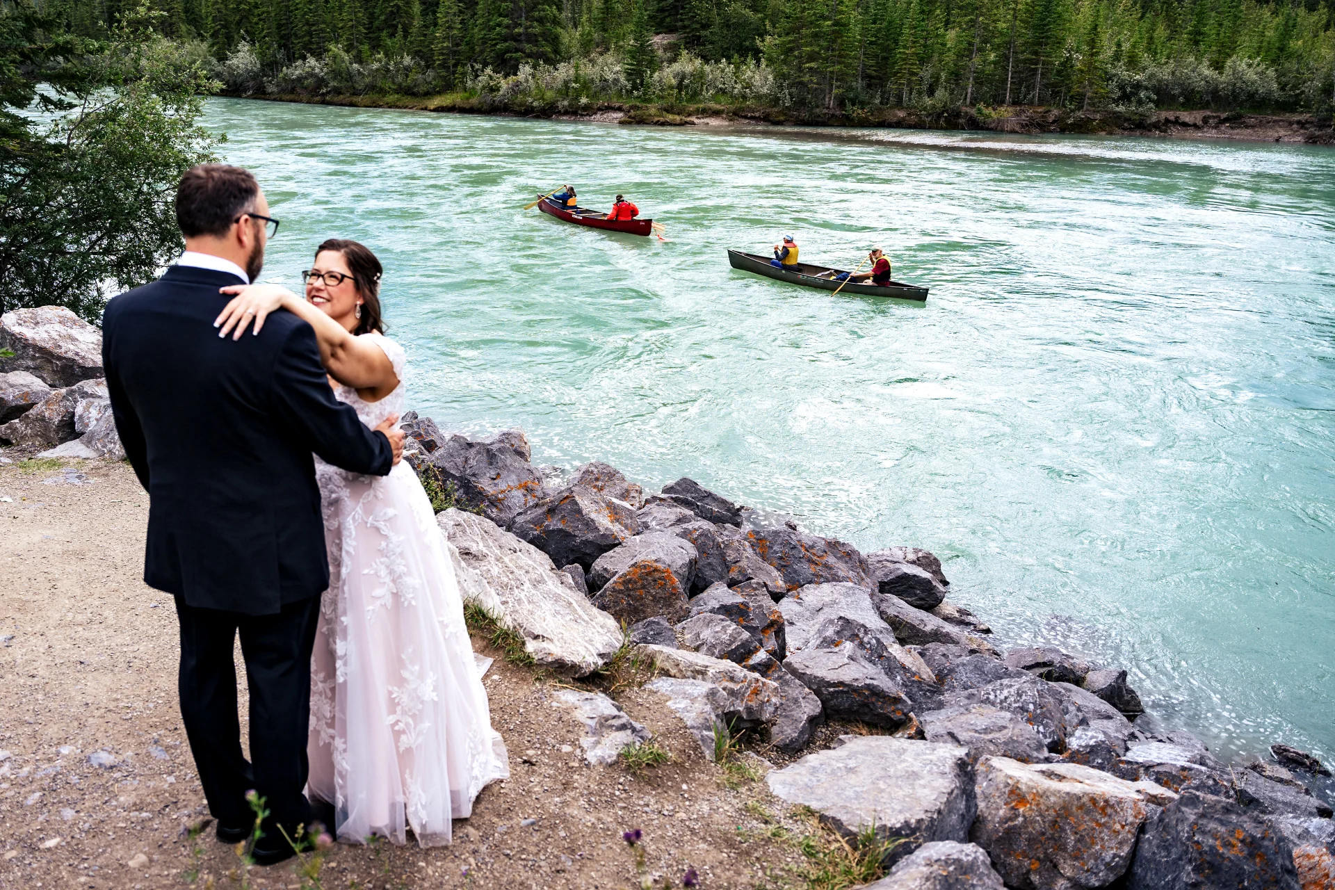 Newlyweds hug by the river in Canmore