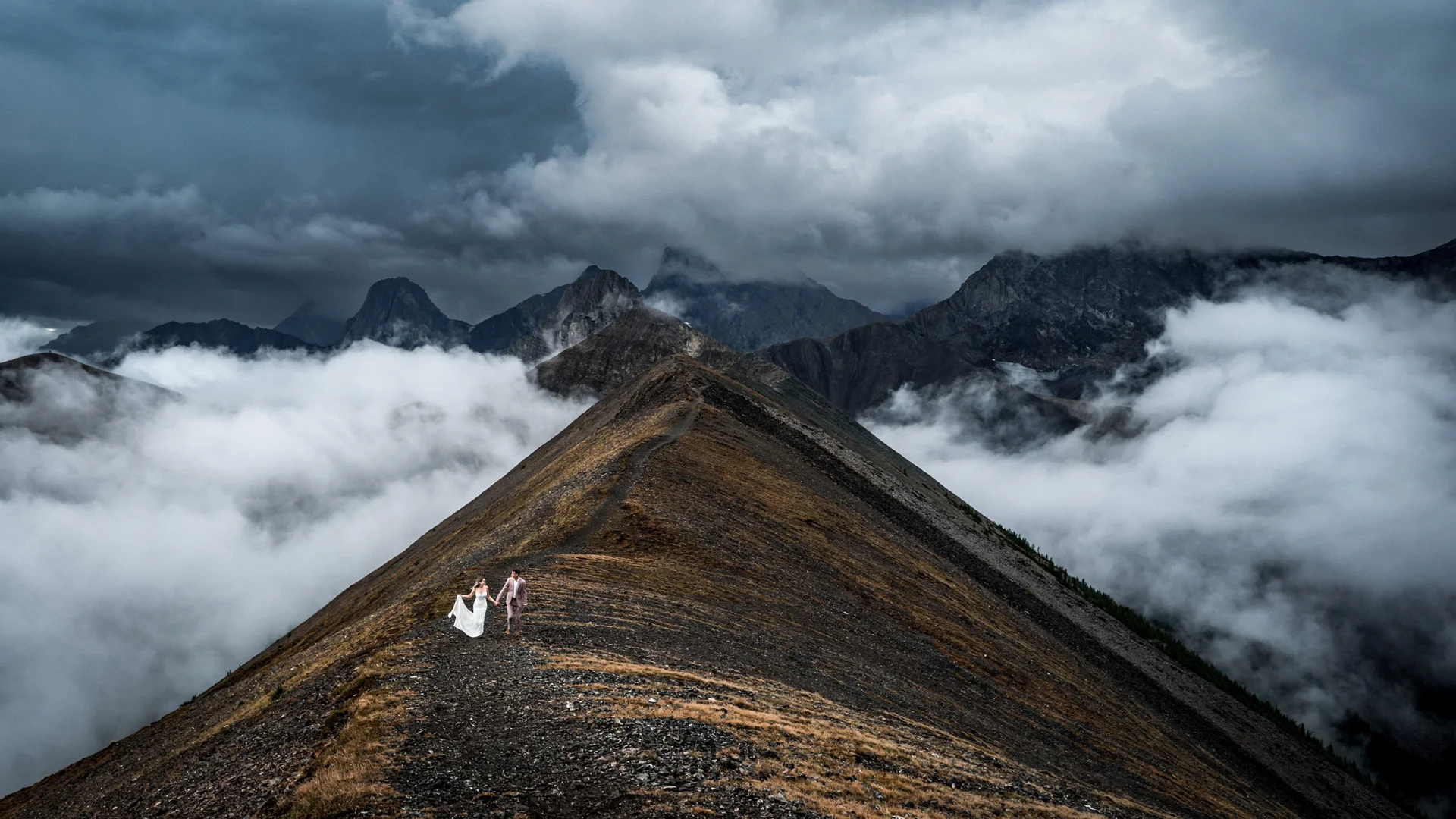 Bride and groom are walking on the ridge of the mountain