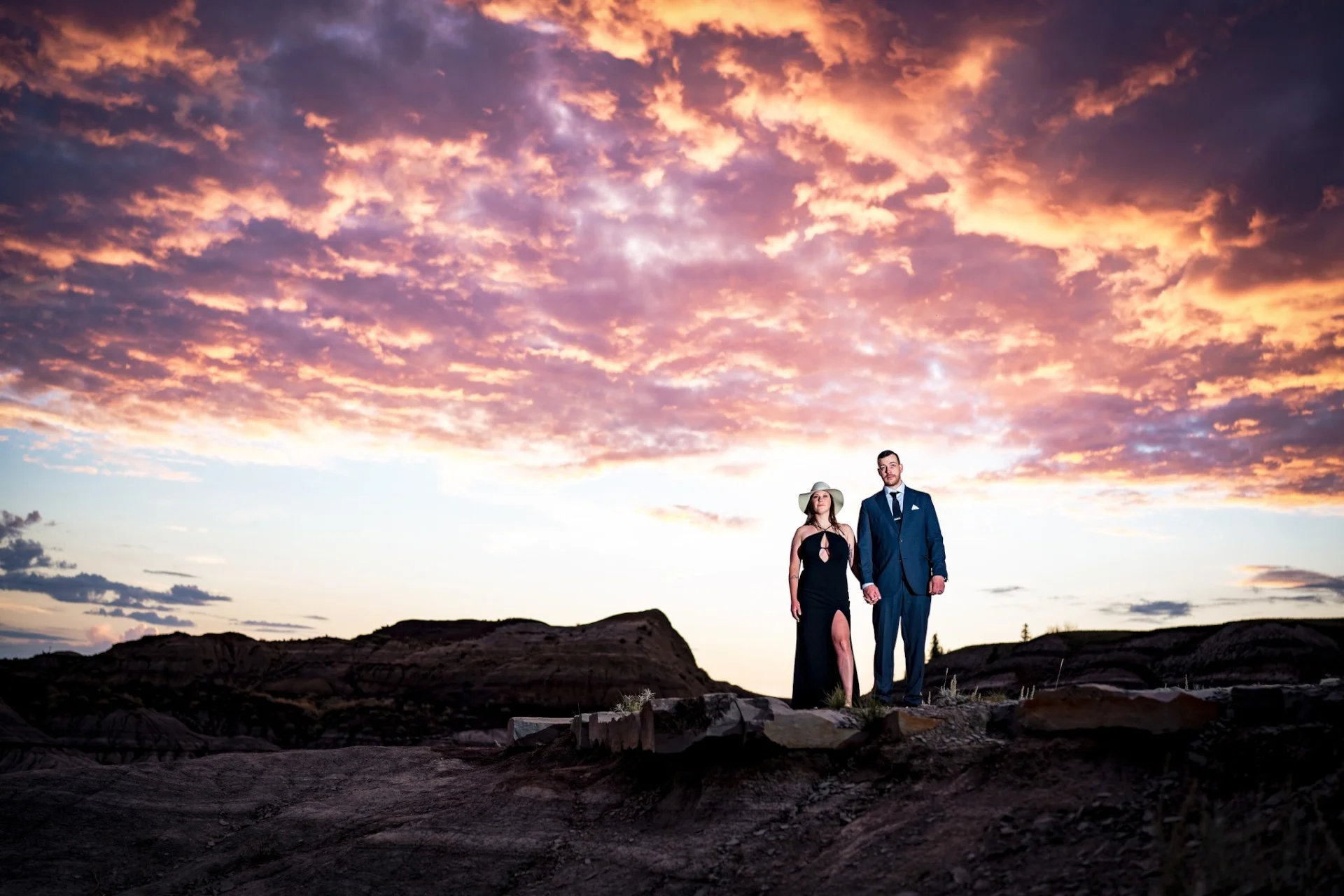 Engaged couple stand on the horseshoe Canyon . Above their heads stunning, colourful clouds.