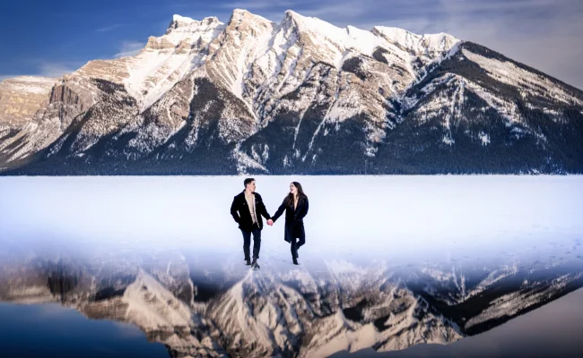 Photograph of the couple walking at the frozen Minnewanka Lake in Banff.