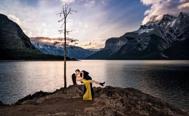 Couple in love dance at Minnewanka Lake during stunning sunrise.