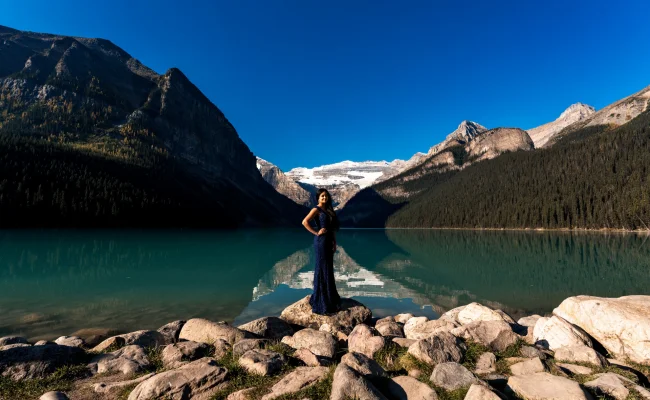 Beautiful in a purple long reass standing at the Lake Louise shore