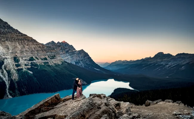 Gentlemen hug his fiance from behind at spectacular location Peyto Lake, surrounded by giant Canadian Rockies