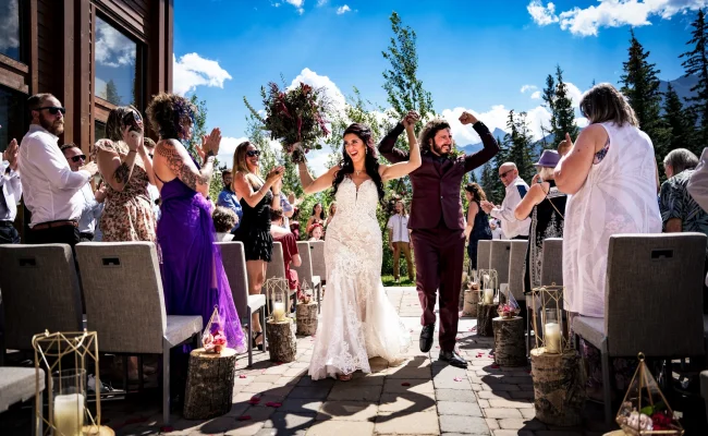 Happy walk of married couple with hands up after Banff Wedding Ceremony