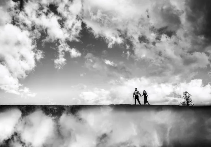 Creative photograph of the walking couple in the sky. Clouds are reflected on the bottom.