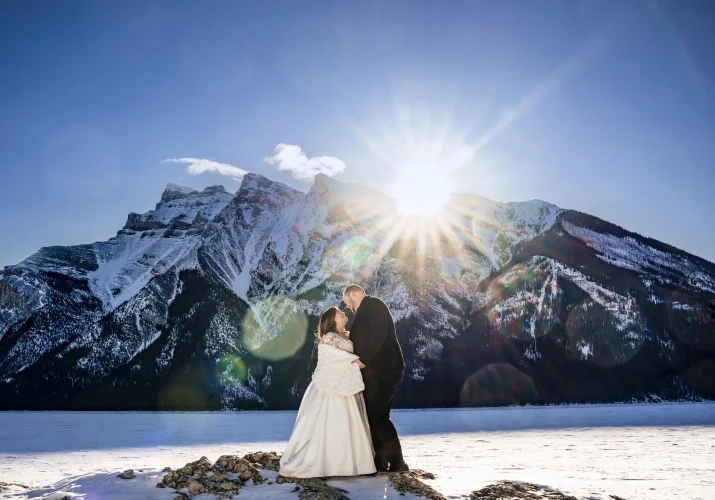 Bride and groom in a hug at the beautiful Minnawanka Lake. Photograph captured by the best Calgary Wedding Photographer.