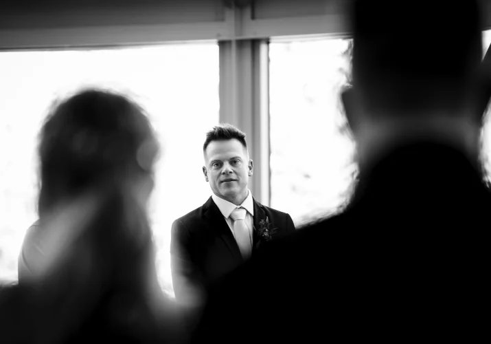 First look of the groom while the bride walking down the aisle in black and white.