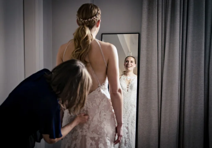 Getting ready time before Banff Wedding Ceremony, Mother of the bride helps with her dress while the bride look at the mirror.
