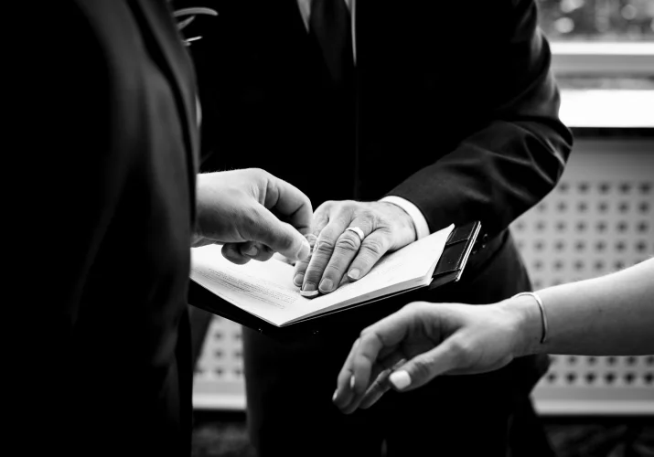 Groom reaches to get the wedding ring from the officiant's book. Banff Wedding Photographer captured the moment of moving hands and the ring.