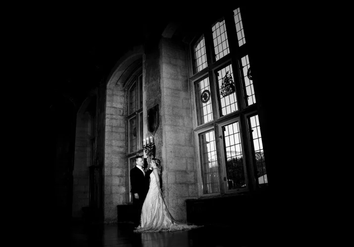 Newlyweds lean on the wall next to the unique widows at Fairmont Banff Springs.