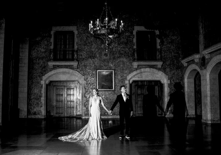 Newlyweds portrait session taken by Banff Wedding Photographer in the ball room at Fairmont Hotel. They fold their hands, above them stunning chandelier.