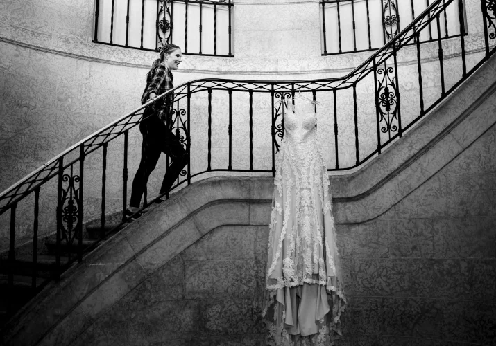 The bride walking up the stairs at Fairmont Banff Hotel. Her wedding dress hanging on the rails.
