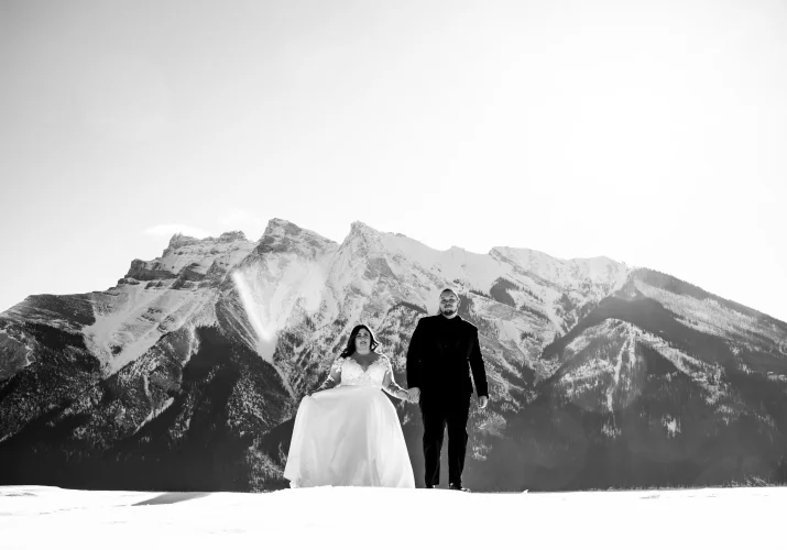 Black and white Banff Wedding Photography of the newlyweds walking in the mountains and holding their hands.
