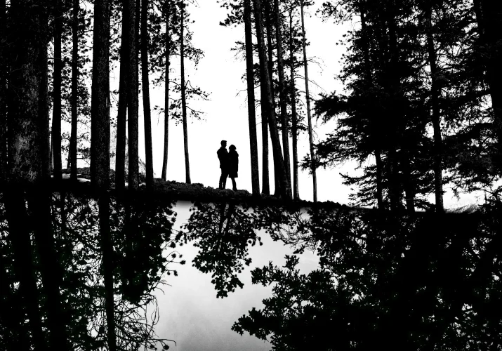 Engaged couple in Banff standing in a hug, surrounded by the forest.
