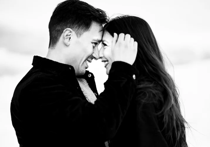 Romantic photograph of the man and his fiancee looking at each other while he brushes her hair.