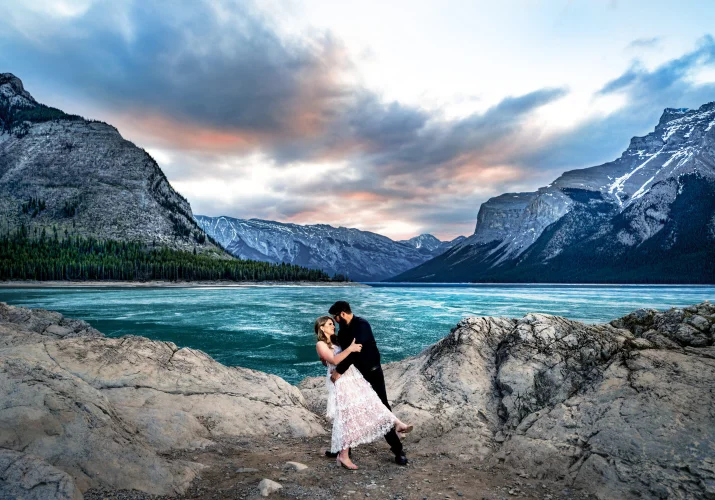 Engaged couple dance at the frozen Minnewanka Lake during amazing sunrise.