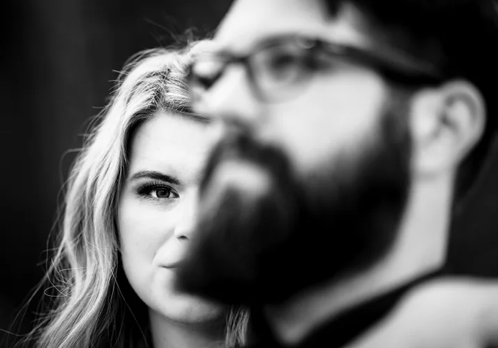 Creative photograph in black and white of the engagement couple when a girl standing behind her fiance with a protective look.