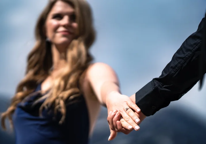 Photograph of the couple holding their hands with the focus on the giant engagement ring.