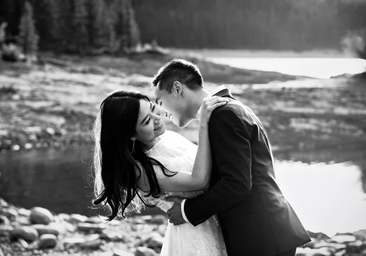 Real moments captured by Banff Wedding Photographer of the engaged couple laughing and hugging at Minnewanka Lake.