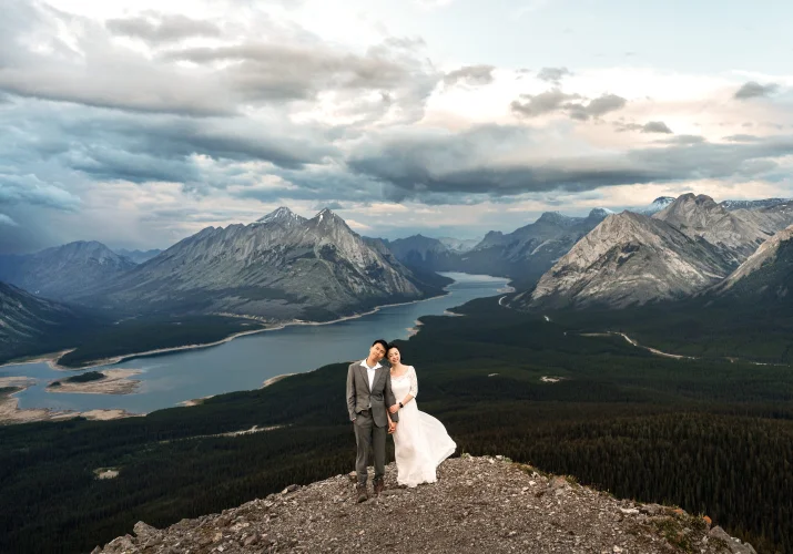 Newlyweds in the mountains looking at the camera and smile.