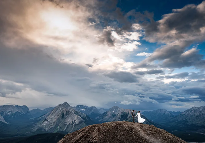 Hiking adventure during the sunset in the Canadian Rockies. Photo of the newlyweds in Banff on the top of the mountain.