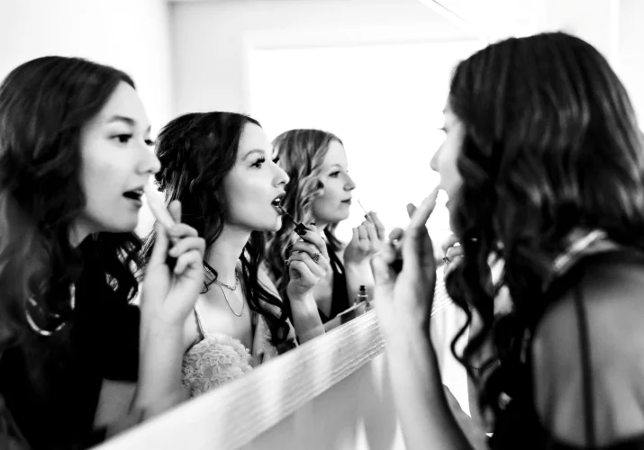 bride and bridesmaids fixing their make up in front of the big mirror