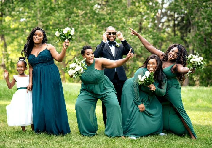 Bridal party lift the hands up while the groom fixes his glasses. Funny bridal party photography taken by Calgary Wedding Photographer.