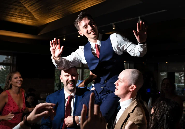 Best man and one of the guest lift the groom up during dance floor at the Calgary Wedding