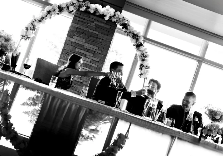 Creative photograph with the reflection of the wedding couple and the guests raising the classes