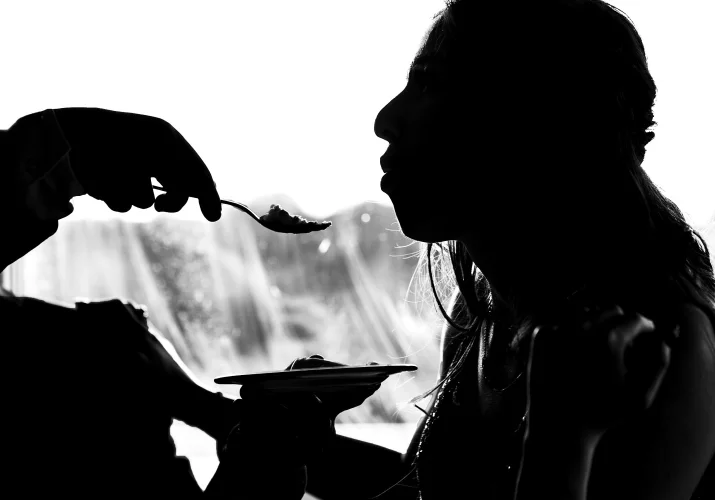silhouette photograph of the bride being feed with the piece of the wedding cake