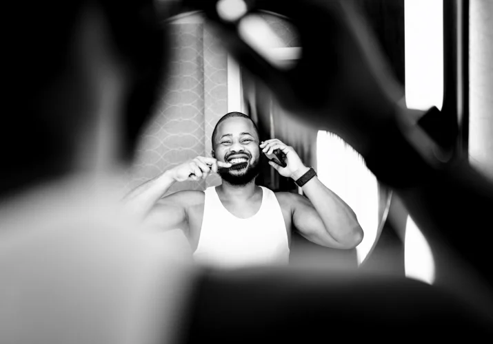The groom brushes teeth and talk on the phone at the same time. Funny photograph taken by Calgary Wedding Photographer.