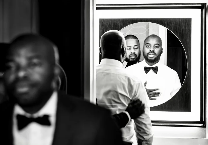 The groom and best man in from of the mirror getting ready before Calgary Wedding Ceremony.