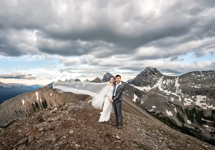 Bride and groom in a hug looking in the camera in the Canadian Rockies.