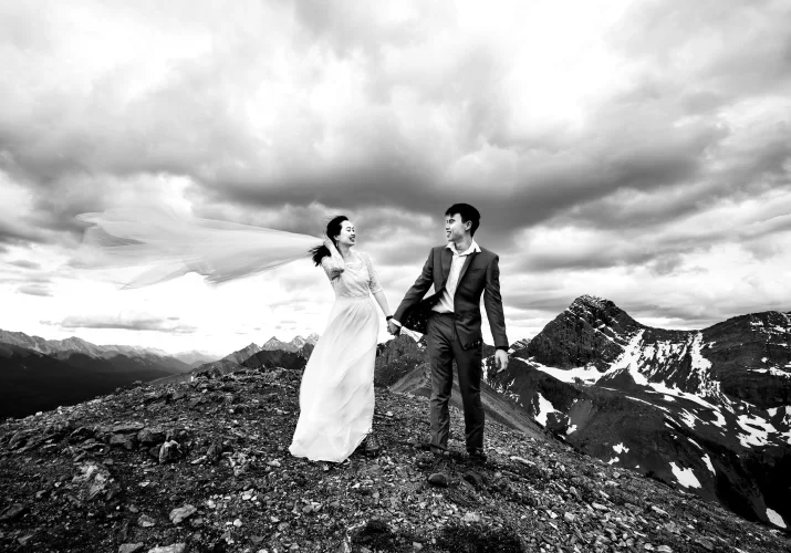 Newlyweds walk at the ridge on the mountain in Banff.