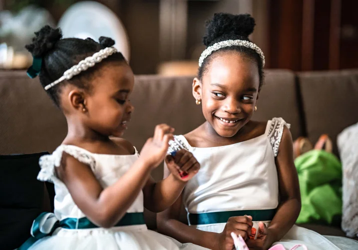 Flower girls laughing to each other before the wedding ceremony.