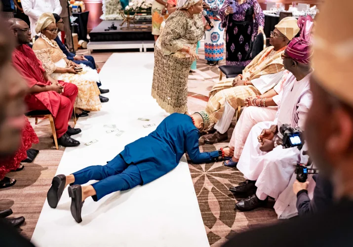 Groom laying on the floor and touches his parents feet during Nigerian ritual on the wedding day.
