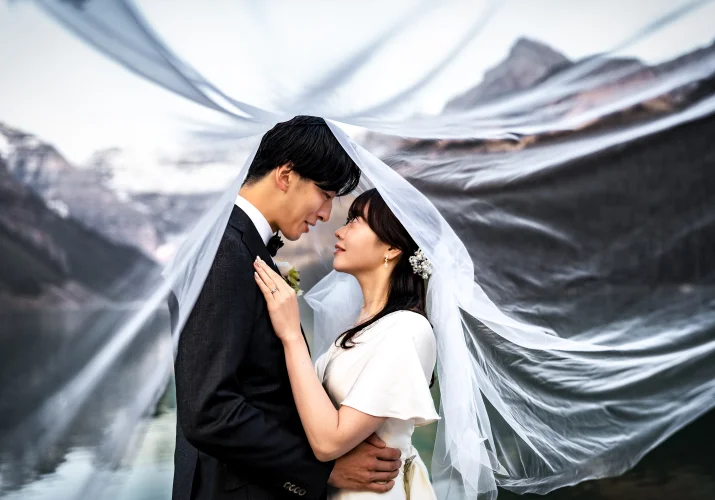 Bride and groom look at each other under the veil.