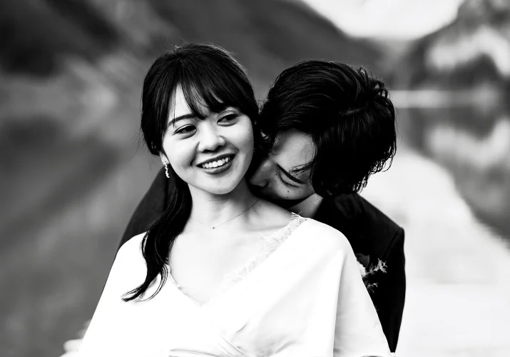 Groom kisses his wife's neck.