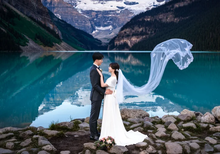 Bride and groom look at look other while the wing blow the bride's veil.