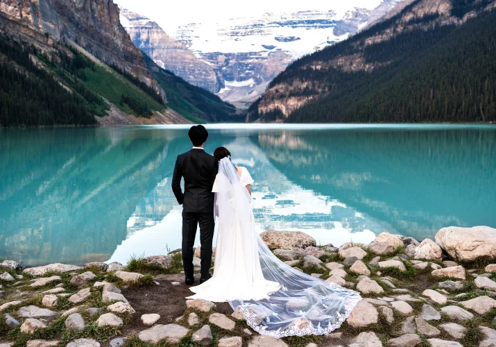 Newlyweds adore the beauty of the stunning Lake Louise. Photo taken from being by Banff Wedding Photographer.