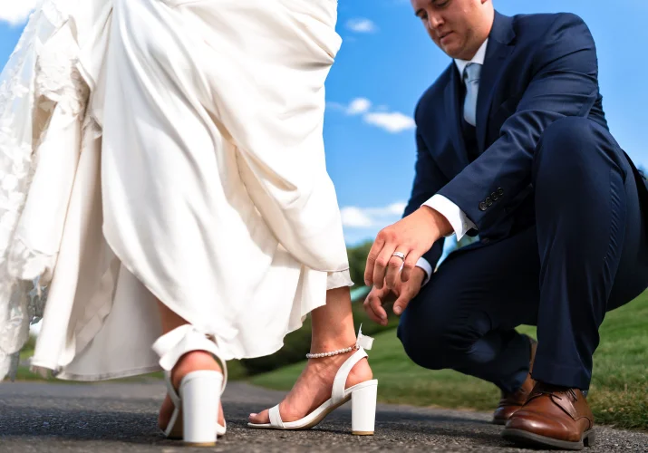 The groom fixes the bride's shoe.