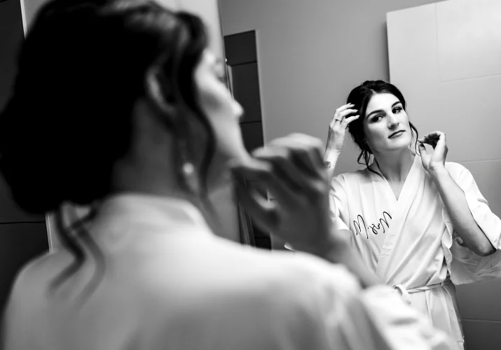 the bride looks at the mirror and fixes her hair.